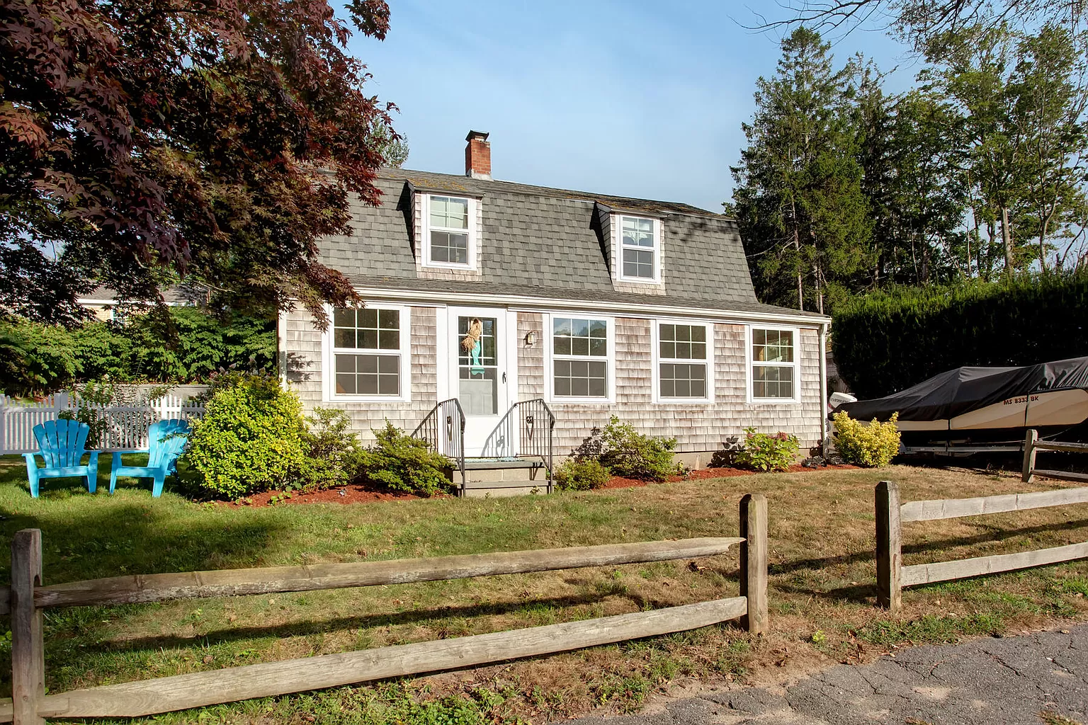 Front of Olde Millie — gambrel roof, red front door, white picket fence.