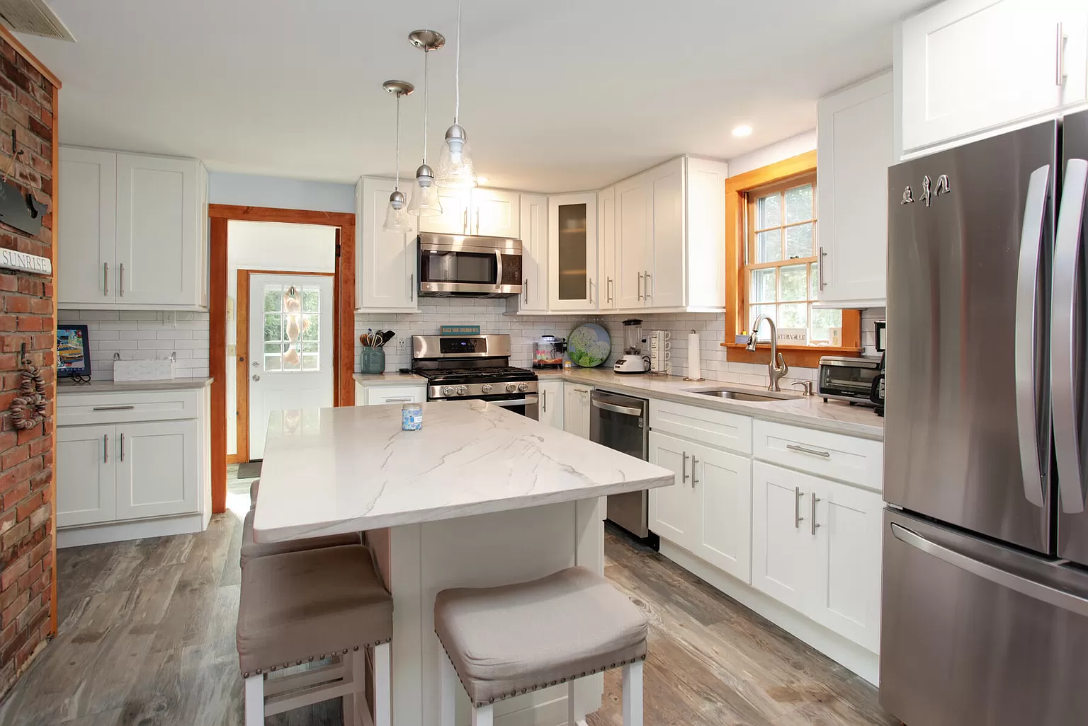 Kitchen island with exposed brick wall and pendant lighting.